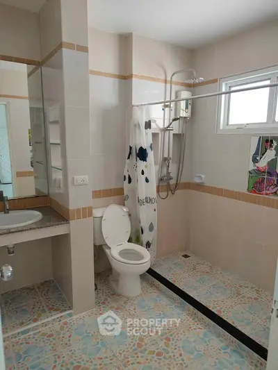 Modern bathroom with shower, toilet, and stylish tile flooring in a bright setting.