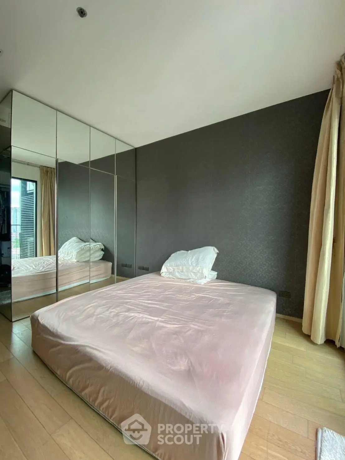 Spacious bedroom with mirrored wardrobe and large window for natural light.