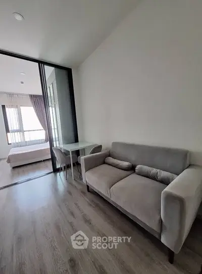 Modern apartment interior with cozy living room and bedroom, featuring sleek furniture and natural light.