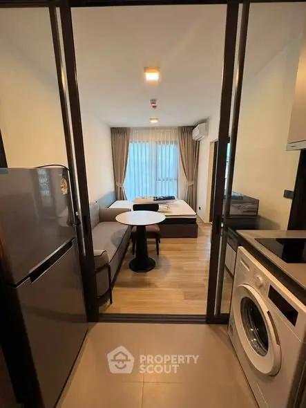 Modern studio apartment with open layout, featuring a cozy living area and compact kitchen with appliances.