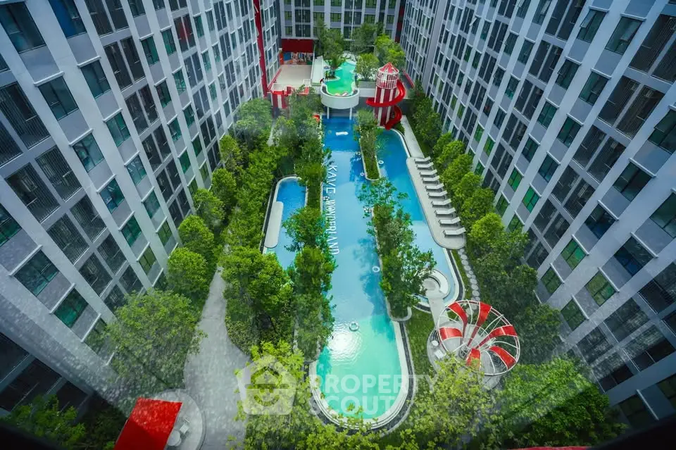 Stunning aerial view of modern apartment complex with lush garden and inviting swimming pool.