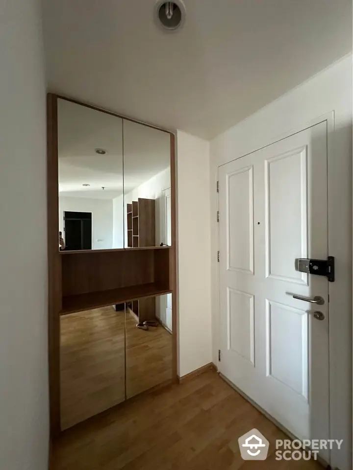 Modern apartment entrance with mirrored closet and secure door