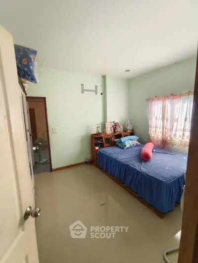 Cozy bedroom with natural light and simple decor, perfect for relaxation and comfort.