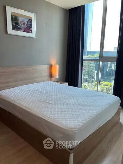 Modern bedroom with large window and city view, featuring a stylish bed and contemporary decor.