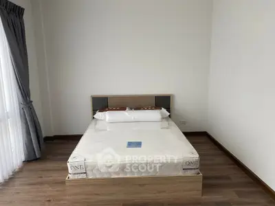 Spacious bedroom with modern bed and wooden flooring in a bright apartment.