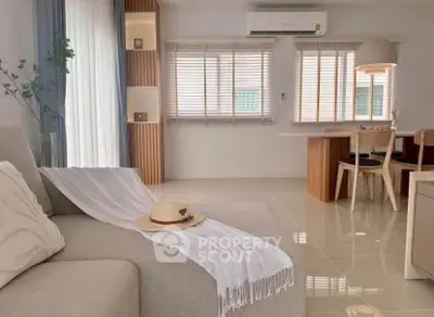 Modern living room with elegant decor and natural light, featuring a cozy sofa and stylish dining area.