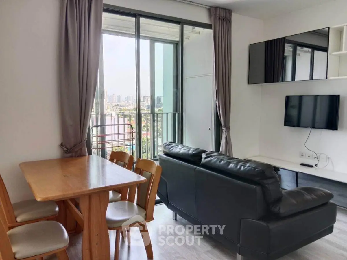 Modern living room with balcony view, sleek furniture, and natural light in urban apartment.