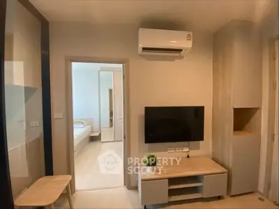 Modern living room with air conditioning and wall-mounted TV, leading to a bright bedroom.