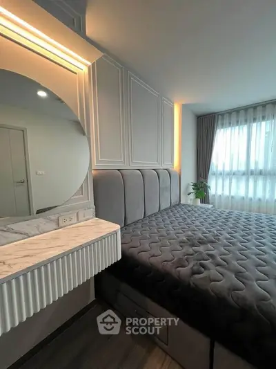 Modern bedroom with stylish decor and natural light, featuring a plush bed and elegant vanity area.