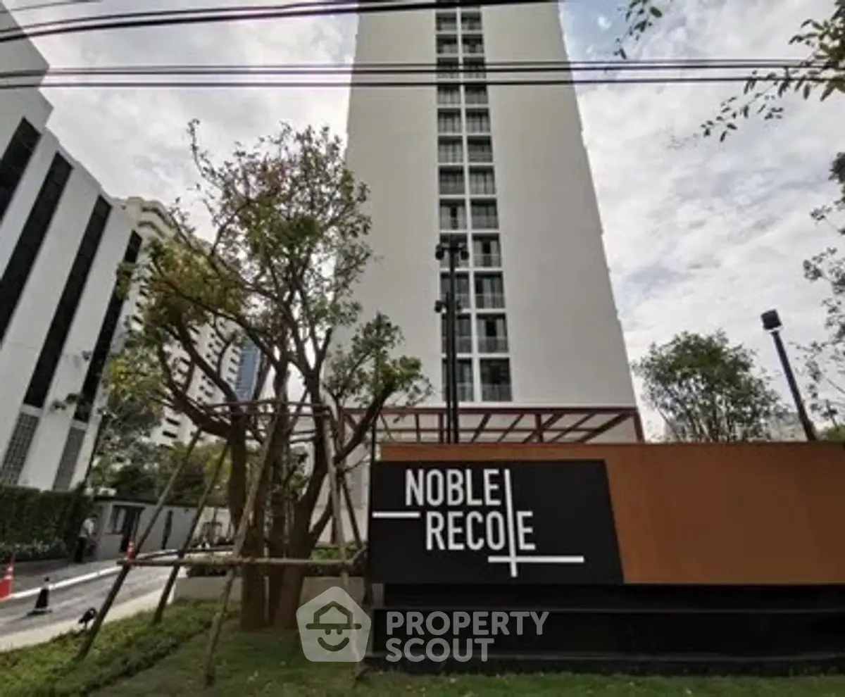 Modern high-rise building with lush landscaping and sleek signage