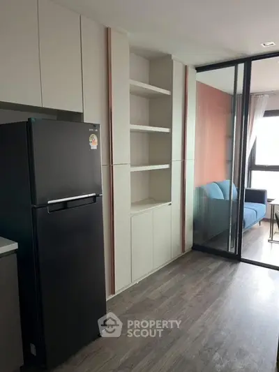 Modern apartment kitchen with sleek black fridge and open shelving
