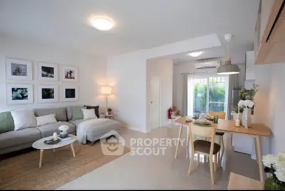 Modern open-plan living room with stylish decor and dining area, featuring natural light and contemporary furniture.