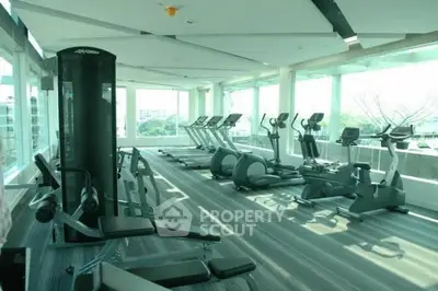 Modern gym with state-of-the-art equipment and panoramic windows in luxury residential building.