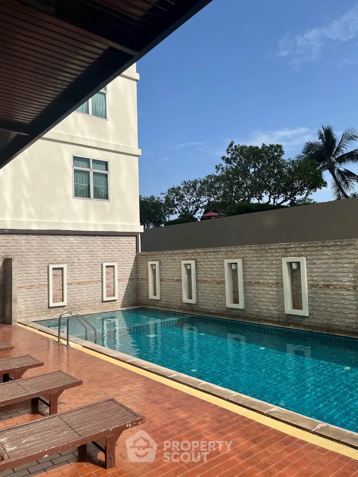 Luxurious apartment building with a serene outdoor pool and sunbathing area.