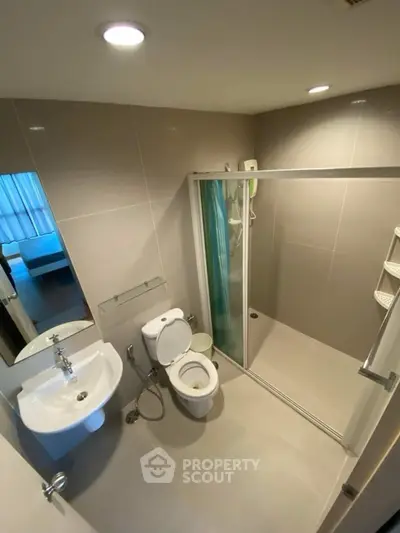 Modern bathroom with shower enclosure and sleek fixtures in a contemporary apartment.