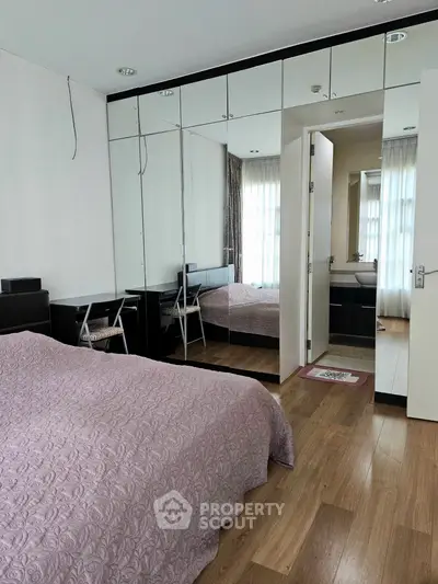 Spacious bedroom with mirrored wardrobe and ensuite bathroom, featuring elegant decor and natural light.