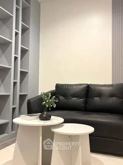 Modern living room with sleek black sofa and stylish white coffee tables, perfect for contemporary urban living.