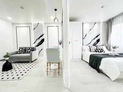 Modern open-plan living room and bedroom with stylish decor and monochrome accents.