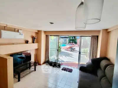 Spacious living room with pool view, modern decor, and ample natural light.