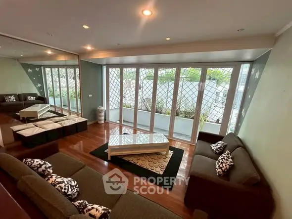 Spacious living room with large windows and modern furniture, offering a serene garden view.