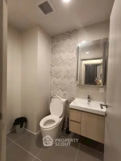 Modern bathroom with sleek design, featuring a toilet and stylish vanity in a contemporary apartment.