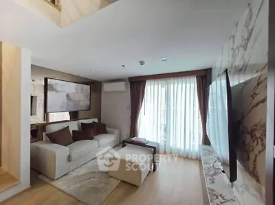 Modern living room with elegant decor and large TV, featuring a cozy sofa and natural light.