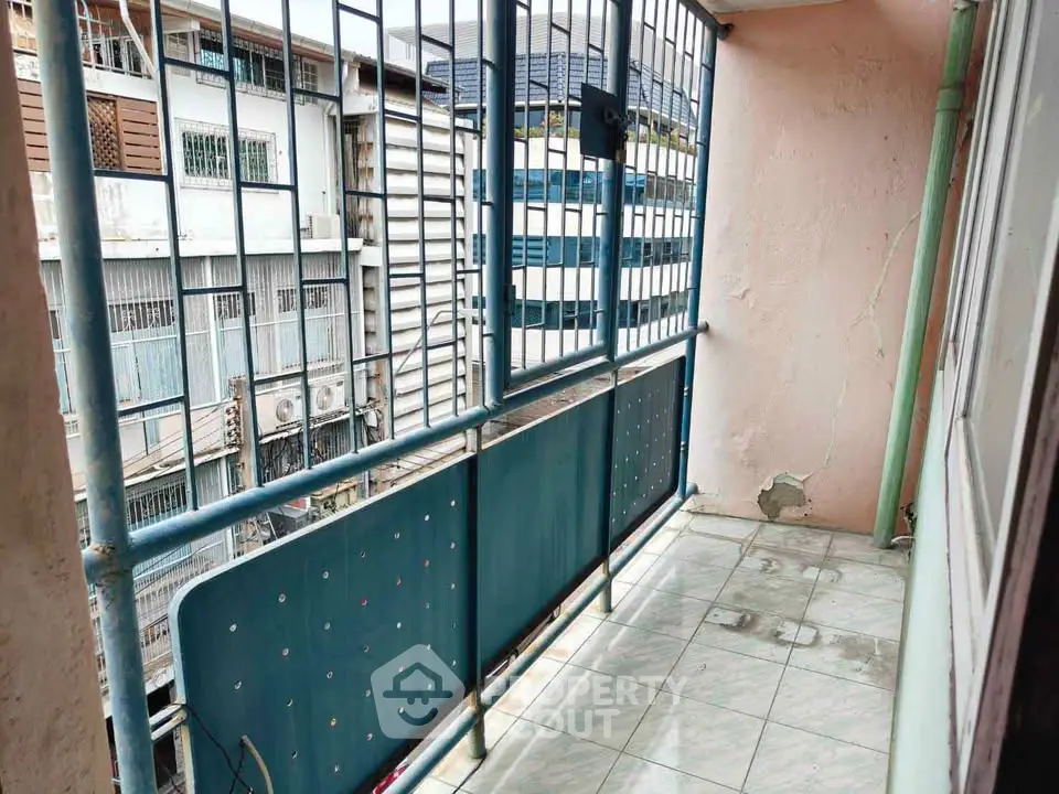 Charming urban balcony with tiled floor and metal railing, perfect for city views.