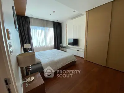Spacious modern bedroom with wooden flooring and large window for natural light.
