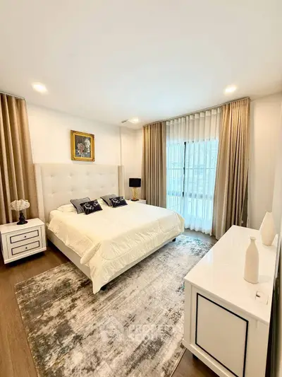 Luxurious bedroom with elegant decor and large window, featuring plush bedding and stylish furniture.