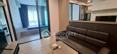 Modern living room with sleek design and open view to bedroom, featuring stylish furniture and natural light.