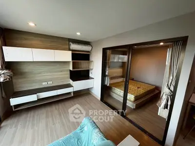 Modern apartment interior with open living room and bedroom, featuring sleek wood flooring and stylish built-in storage.