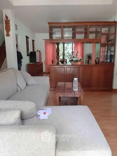 Spacious living room with cozy sofa and wooden furniture, perfect for relaxation and entertaining guests.