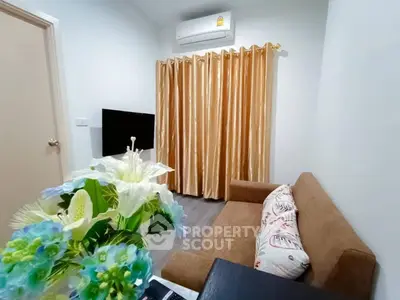 Cozy living room with brown sofa, floral decor, and air conditioning, perfect for relaxation.