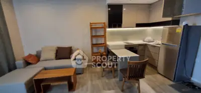 Modern open-layout kitchen and living room with stylish furniture and appliances.