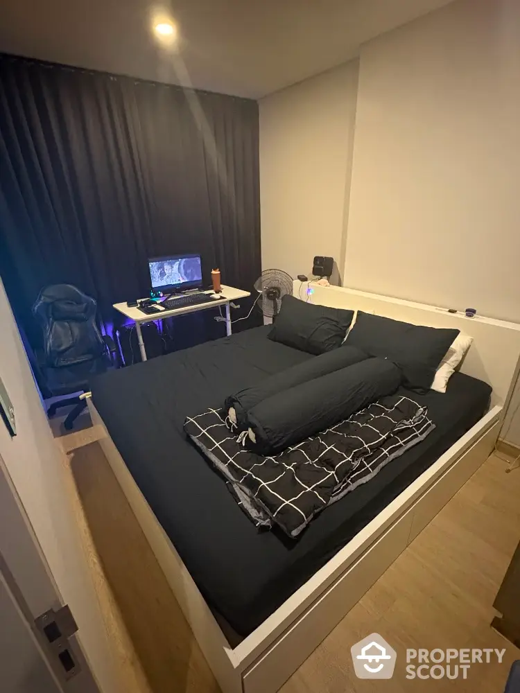 Modern bedroom with gaming setup and stylish black bedding