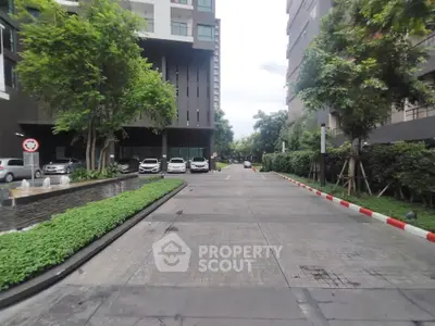 Modern apartment building entrance with lush greenery and parking area
