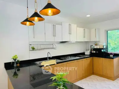 Modern kitchen with sleek black countertops and stylish pendant lighting.