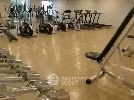 Spacious gym with modern fitness equipment in luxury apartment complex.