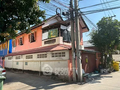 Charming two-story house with vibrant exterior and lush greenery, perfect for family living.