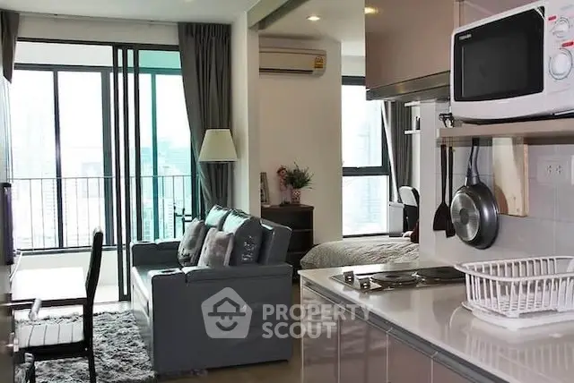Modern open-plan living room with kitchen and balcony view in urban apartment.