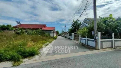 Charming suburban street view with houses and lush greenery under a clear blue sky.