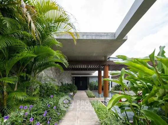 Modern architectural entrance with lush greenery and sleek design.