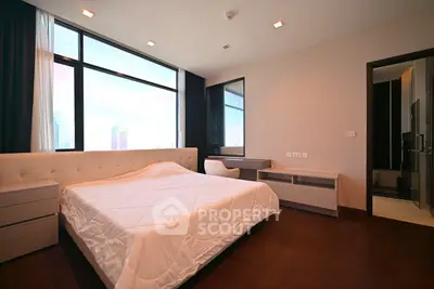Spacious modern bedroom with large windows and elegant furnishings in a high-rise apartment.