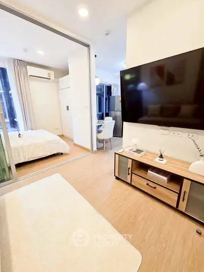 Modern living room with open view to bedroom, featuring sleek TV setup and stylish decor.