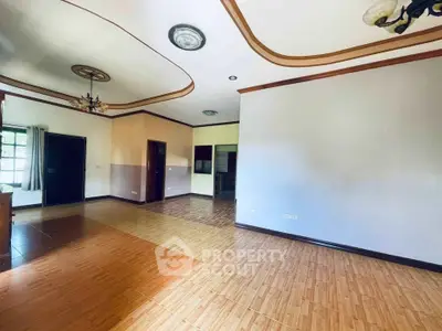 Spacious living room with elegant ceiling design and wooden flooring, perfect for modern living.