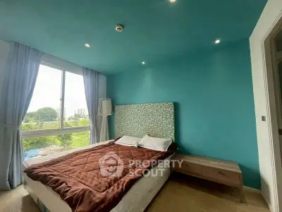 Cozy bedroom with teal accent wall and large window offering scenic views.