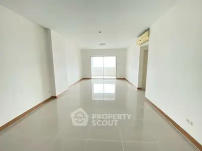 Spacious empty living room with glossy tiled floors and air conditioning.