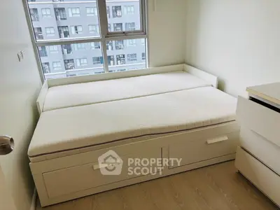 Modern bedroom with a sleek white bed and large window offering city views.