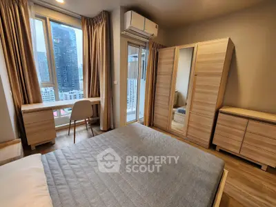 Modern bedroom with city view, featuring stylish furniture and large windows for natural light.