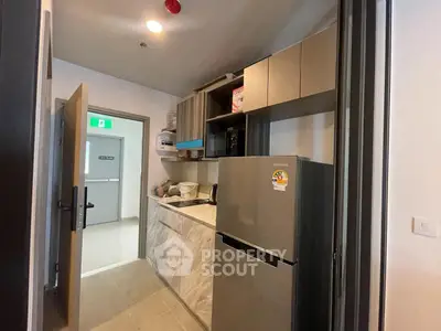 Modern kitchen with sleek cabinetry and stainless steel fridge in compact layout.